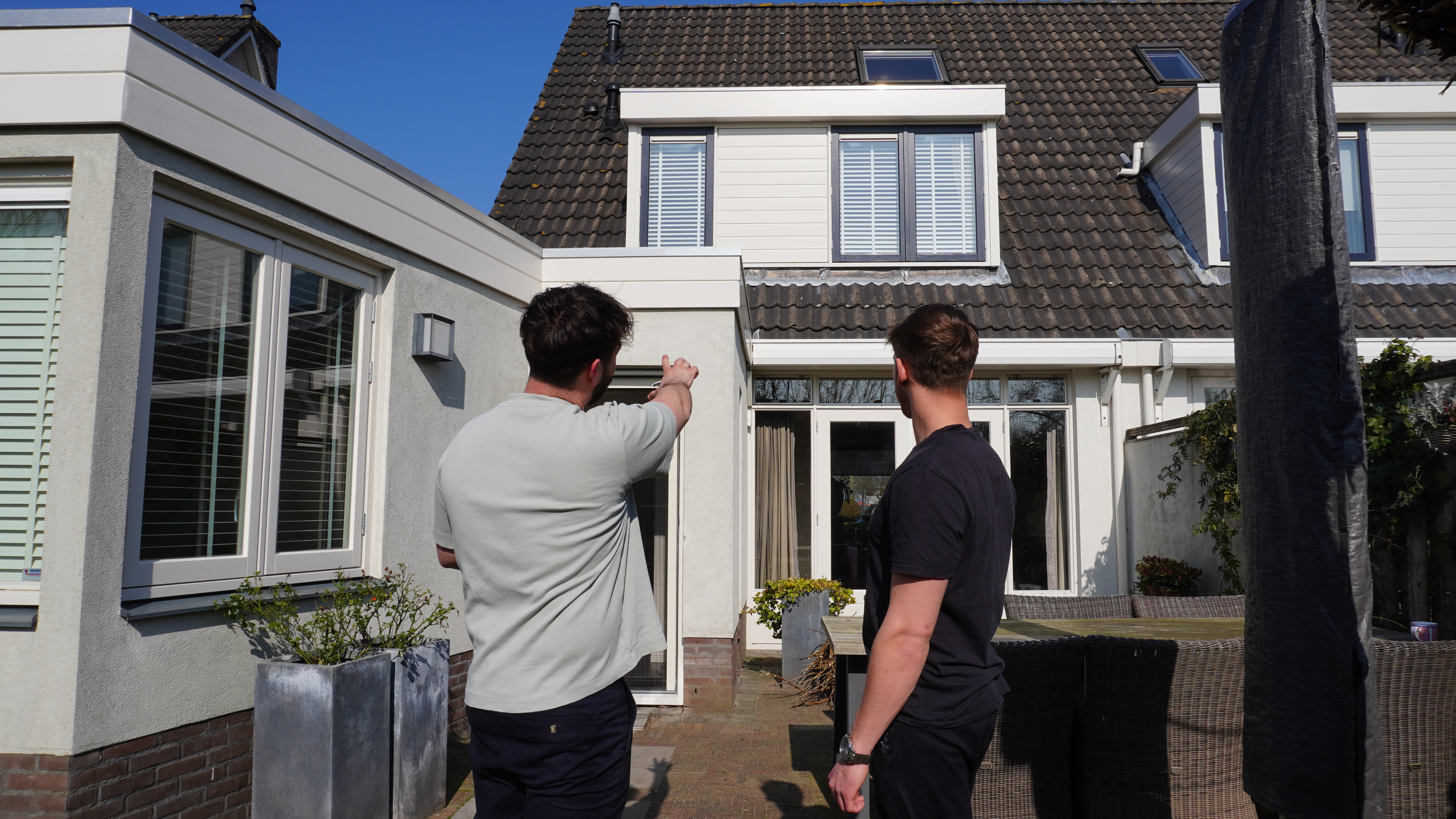 Energieadviseur van Ecofinn beoordeelt de energieprestaties van een woning en bespreekt verduurzamingsmogelijkheden met een klant in de achtertuin.